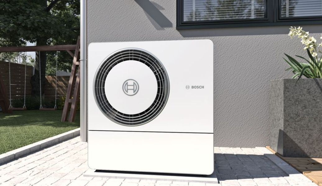 helle Wärmepumpe vor Haus mit Bosch Logo